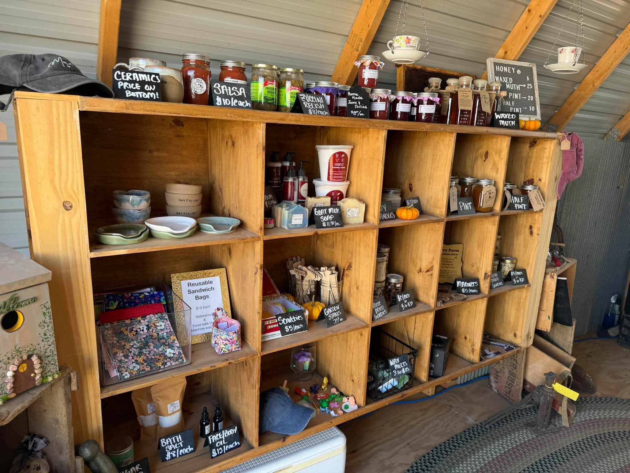Wooden cubby shelves of jarred salsa, honey, ceramics, and handmade soaps